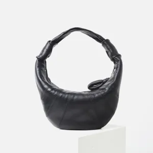 Vista de cerca del bolso hobo croissant de cuero negro con detalles de la correa de hombro.