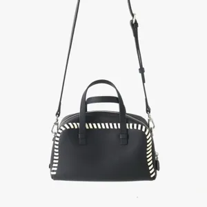 Sac Boston en cuir noir avec bordure tressée blanche contrastée et bandoulière réglable.