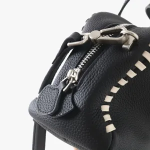 Detail de sac boston en cuir noir avec belles coutures blanches et quincaillerie argente