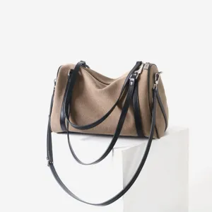 Détail du sac Boston en toile et cuir, montrant des coutures fines et des fermetures éclair.