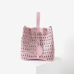 Élégant sac seau en cuir rose perforé avec poignée supérieure et cordon de serrage.
