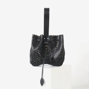 Vue de détail du sac seau noir en cuir avec un motif ajouré complexe et découpe laser.