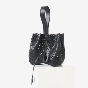 Vue détaillée du sac seau en cuir noir ajouré au laser avec poignée et cordon de serrage.
