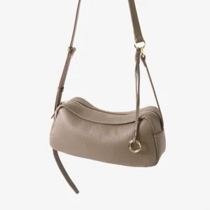 Gros plan sur le sac cylindrique en cuir souple avec fermeture éclair et anneau en métal.