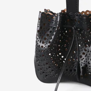 Détail de sac seau en cuir noir avec motif perforé géométrique découpé au laser.