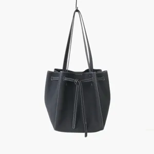 Détail de sac seau en cuir noir montrant des coutures blanches et un nœud coulissant.