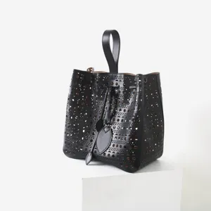 Vue détaillée du sac seau en cuir noir présentant des motifs géométriques ajourés.