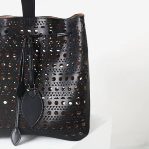 Gros plan sur le sac en cuir noir perforé avec des détails de motifs géométriques.