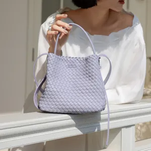 Gros plan détaillé du sac seau tissé violet clair, mettant en valeur sa texture et sa bandoulière.