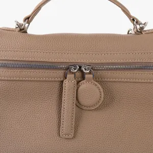 Gros plan détaillé de la fermeture éclair du sac en cuir véritable et grain texturé.