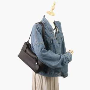 Vue détaillée du sac porté épaule en cuir marron foncé, sac oreiller de navette.