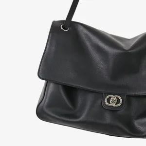Gros plan sur les détails du sac porté épaule en cuir souple avec fermoir métallique.