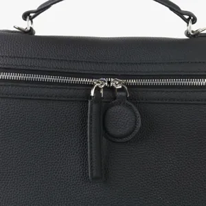 Gros plan détaillé de la fermeture éclair et de la poignée du sac en cuir de vache noir.