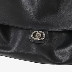 Gros plan sur les details du sac a main en cuir noir avec fermoir anneau en metal argente.