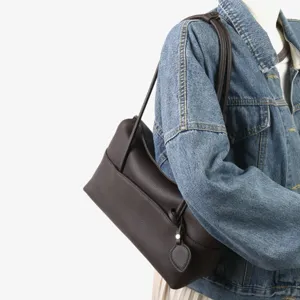 Sac épaule en cuir marron détail montrant texture souple, poignée latérale et design élégant.