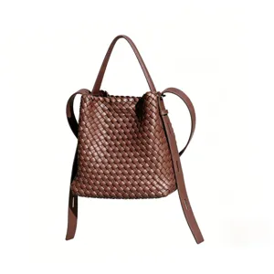 Détail de sac seau en cuir tressé marron montrant un savoir-faire complexe et une longue lanière.
