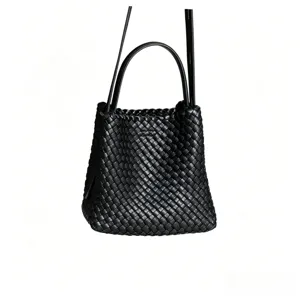 Vue rapprochée du sac seau en cuir tressé noir avec un savoir-faire artisanal et une bandoulière.