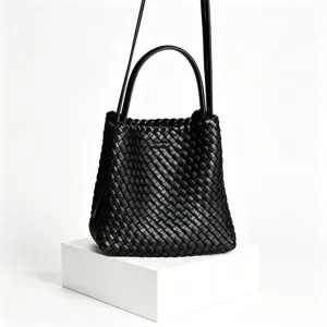 Détail de sac seau en cuir tressé noir, élégant sac bandoulière au design chic et texturé.
