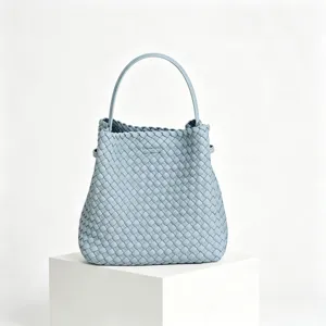 Gros plan sur le sac à main en cuir tressé bleu clair, mettant en valeur les détails et la texture.