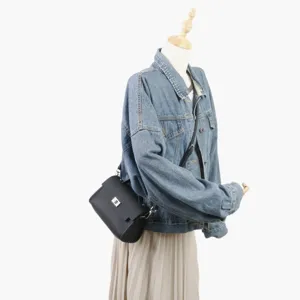 Sac bandoulière noir en cuir présenté sur mannequin avec un élégant design de selle.