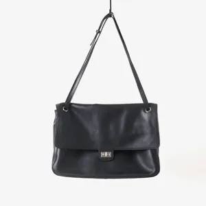 Détail de sac à bandoulière en cuir noir avec texture souple et fermoir métal.