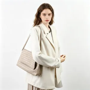 Gros plan détaillé d'un élégant sac à bandoulière en cuir tressé beige sur mannequin.