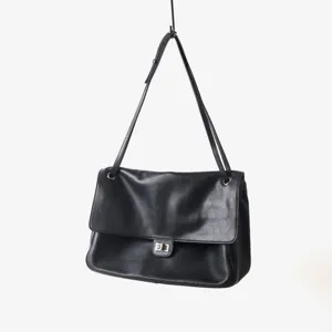 Vue détaillée du sac à épaule en cuir noir avec rabat classique et fermeture à tournante en métal.