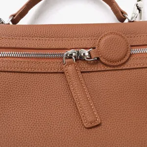 Vue détaillée de la fermeture éclair et de la texture du sac cabas en cuir marron.