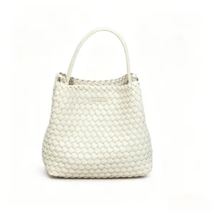 Gros plan sur la texture du sac à main en cuir tressé blanc, artisanat de qualité et finitions.