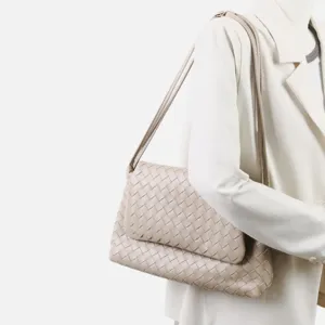 Gros plan détail du sac porté épaule en cuir tressé beige sur mannequin, beau design.