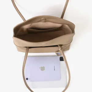 Vue détaillée du sac cabas en cuir beige montrant l'espace intérieur avec un accessoire tablette.