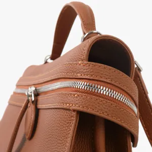 Gros plan detaille de sac a main en cuir marron avec texture fine et fermeture eclair solide.