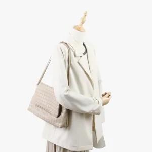 Détail de sac à épaule en cuir tressé beige, élégant design à rabat sur mannequin.