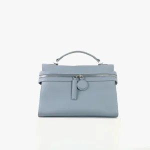 Gros plan du sac à main en cuir bleu clair avec texture fine, fermeture éclair et poignée.