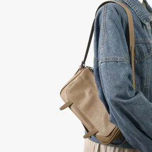 Vue detaillee du sac a epaule en cuir marron de style vintage porte avec une veste en jean.