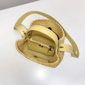 Sac seau chic en cuir tressé jaune beurre avec poignée supérieure et bandoulière.