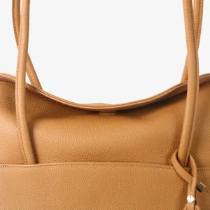 Gros plan détaillé montrant la texture en cuir grainé de qualité et la bandoulière.