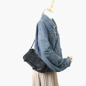 Vue détaillée du sac porté épaule en cuir noir avec design à rabat sur mannequin.