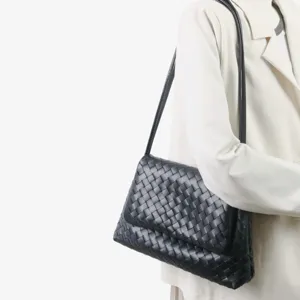 Vue détaillée du sac porté épaule en cuir tressé noir mettant en valeur son design.