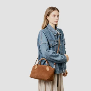 Vue détaillée du sac à main rétro en daim marron porté par le mannequin, montrant le design.