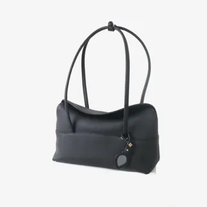 Détail de sac porté épaule noir en cuir souple avec texture vachette et lanières.