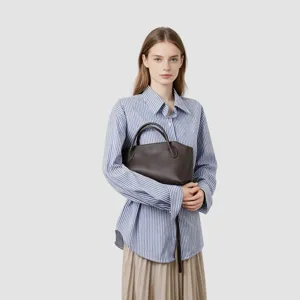 Gros plan sur un sac à main en cuir marron foncé, design rétro élégant avec double poignée.