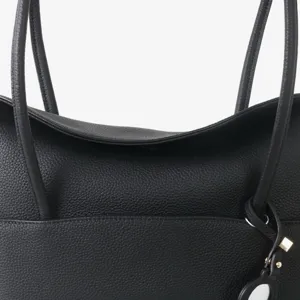 Détail de sac cabas en cuir véritable noir montrant texture grainée et breloque cadenas.