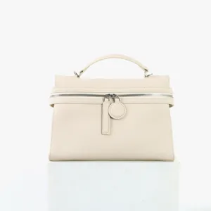 Sac à main beige en cuir doté d'un design structuré en boîte et fermeture à glissière.