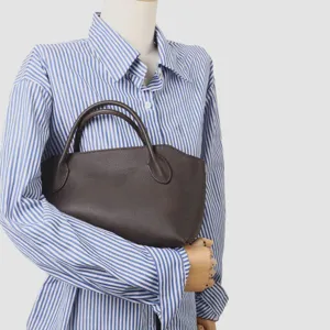 Détail élégant du sac à main en cuir marron foncé montrant la texture et les poignées robustes.