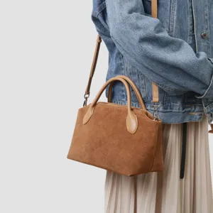 Vue détaillée du sac à main en daim marron avec poignées en cuir lisse et design élégant quotidien.