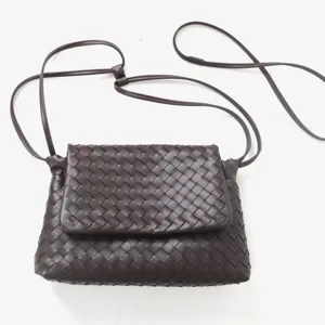 Détail de sac bandoulière à rabat en cuir tressé marron, élégant sac à main texturé.