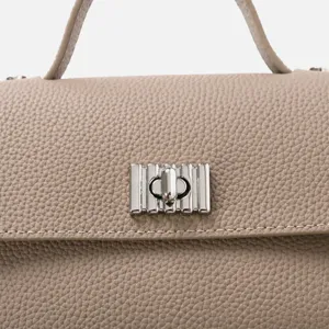 Détail d'un sac à main luxueux en cuir de vachette taupe avec fermoir argenté élégant.