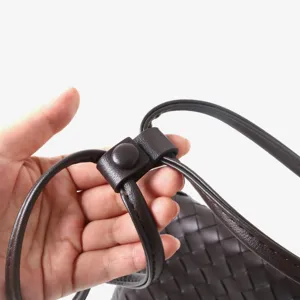 Gros plan détail de la lanière en cuir tissé marron foncé avec fermeture pression.