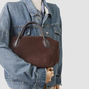 Vue détaillée du sac à main en daim marron mettant en valeur la texture et la poignée.